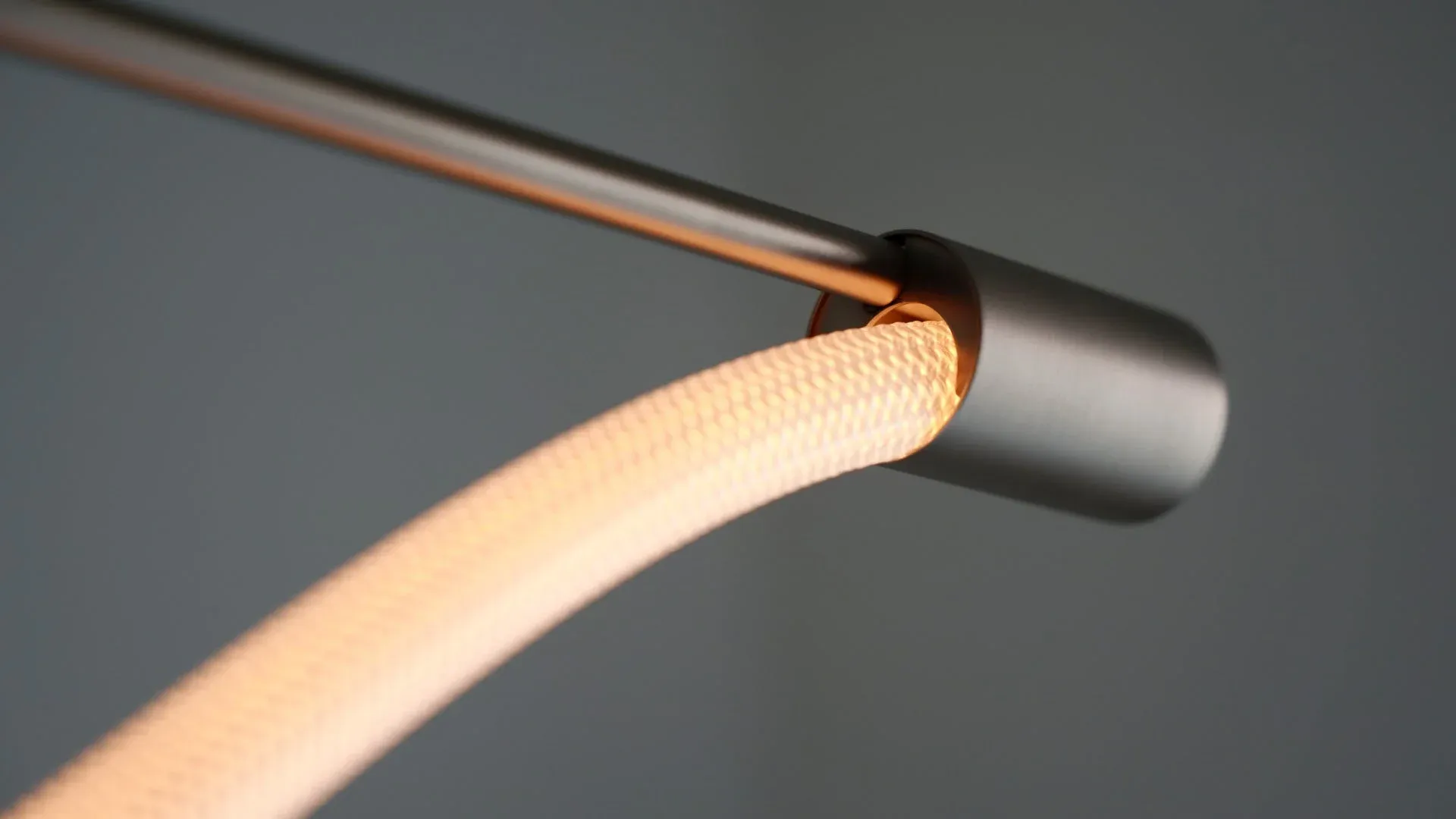 メタリックなチューブから発光する、テクスチャのある柔軟な照明器具のクローズアップ。