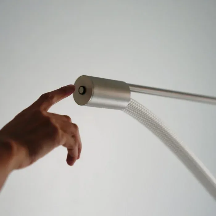 人の指が金属製のモダンなデバイスのボタンに触れようとしている瞬間を捉えています。