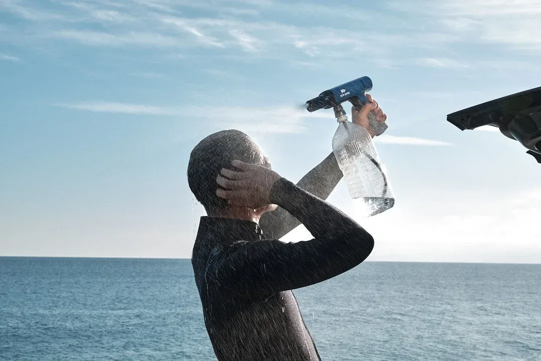 ウェットスーツを着た人がポータブルシャワーで体を洗い流す様子