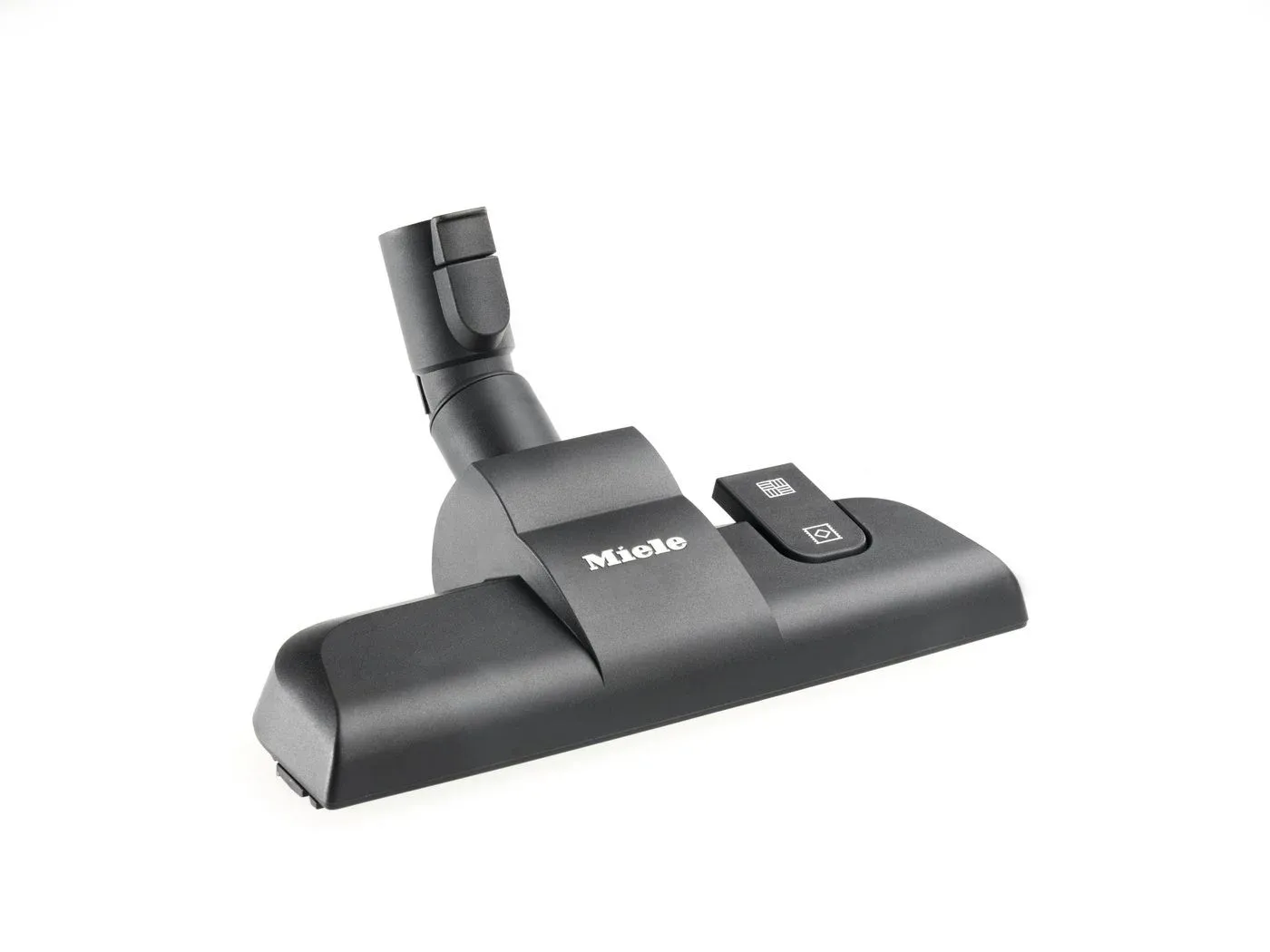 白い背景に置かれた、Mieleブランドの暗い灰色の掃除機ヘッドのクローズアップ写真です。ノズル部分と、床のタイプを切り替えるためのシンボルが描かれたボタンが見えます。