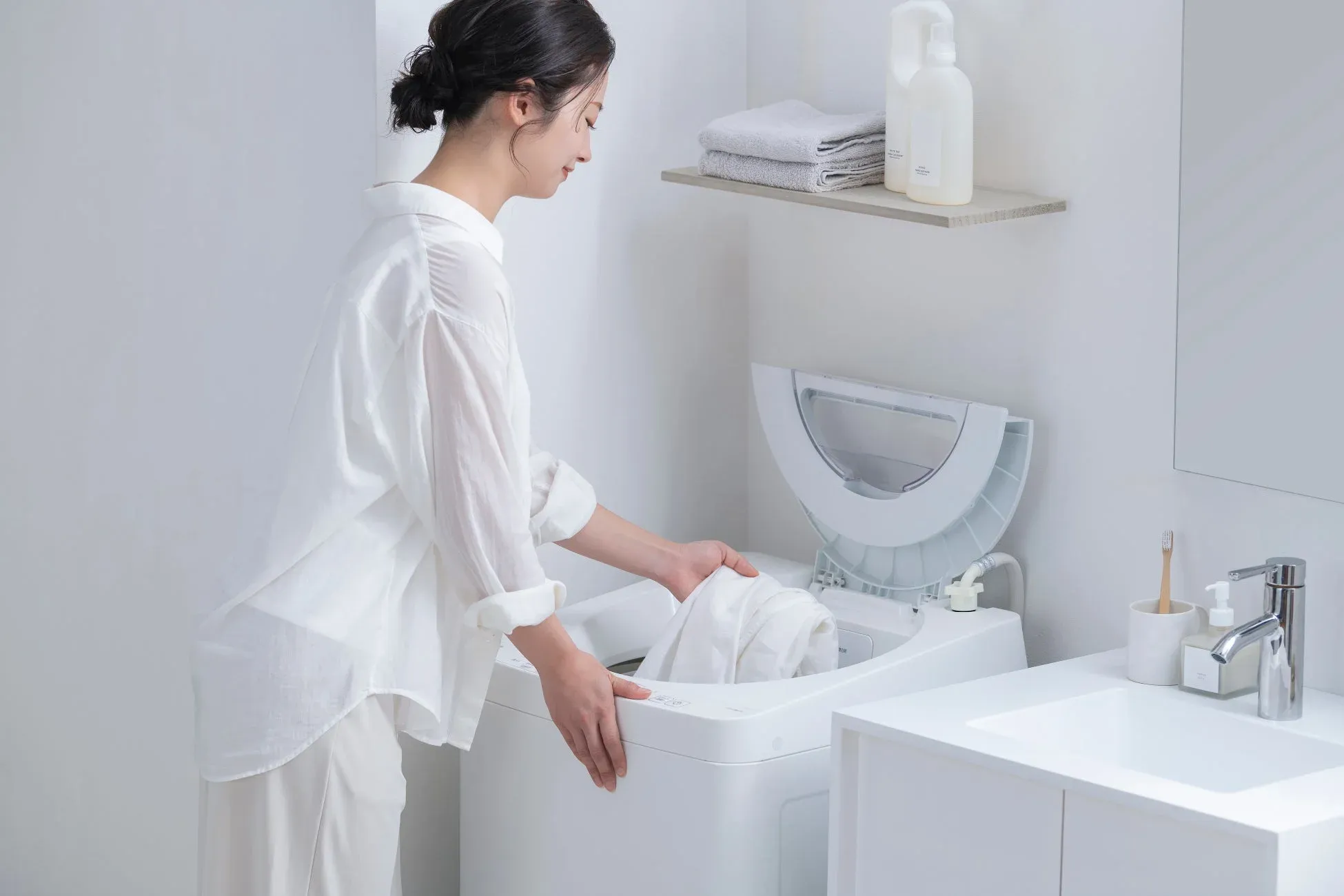 女性が洗濯機に衣類を入れる様子