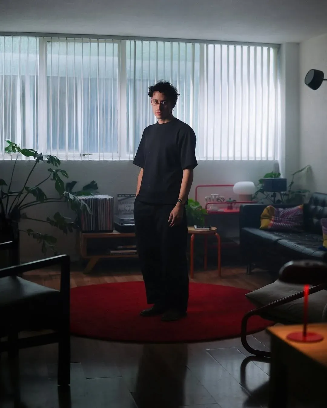 黒い服を着た若い男性がモダンなリビングルームに立っています
