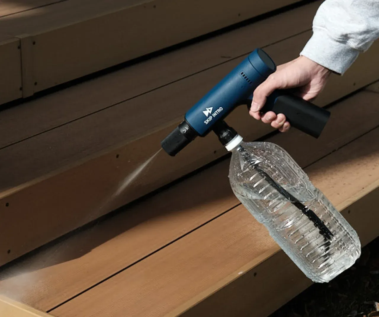 ペットボトルに取り付けられ水が噴射されている洗浄機