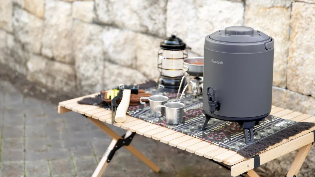 キャンプ用品が並べられた木製テーブルとウォータージャグ