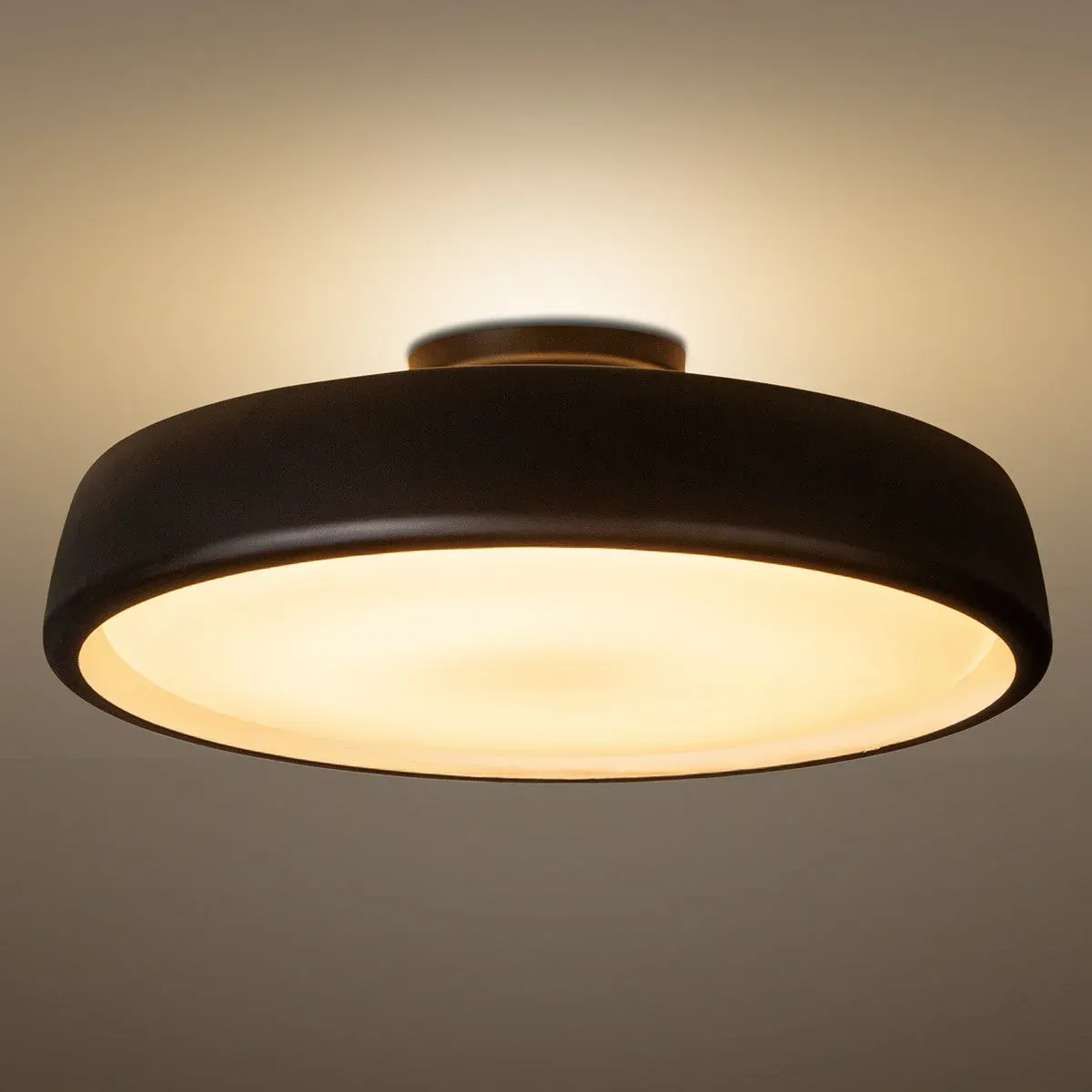 天井に設置された黒いモダンなシーリングライトが、温かみのある光を放っている様子