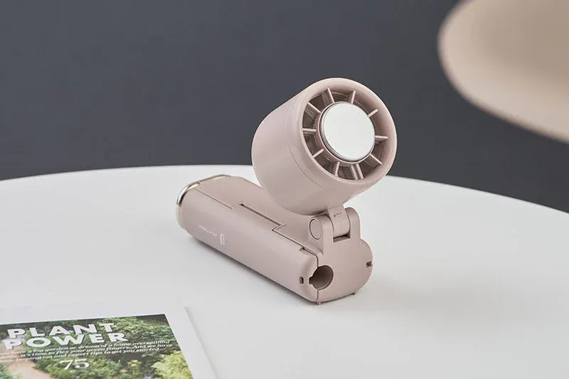 淡いピンク色のポータブル扇風機が白いテーブルの上に置かれている