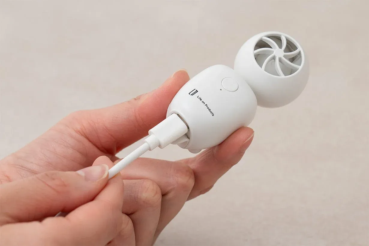 手が白いUSB接続の小型デバイスを握っている画像