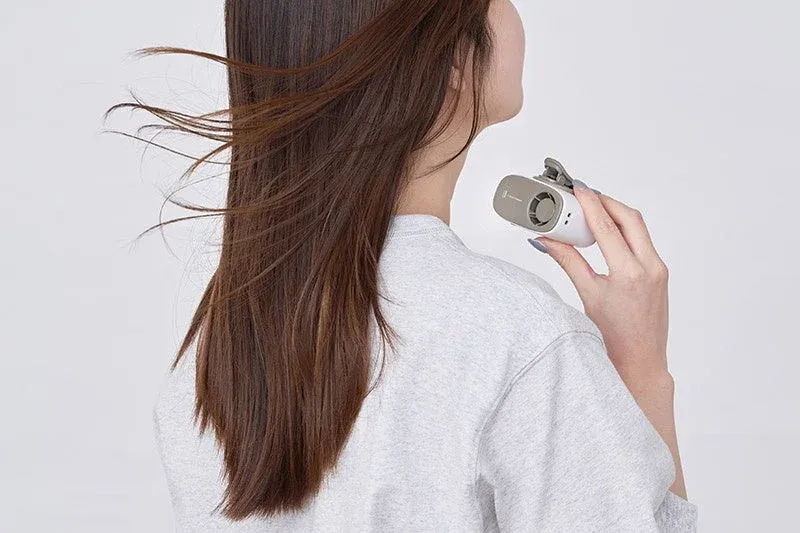 女性が首元に小型のポータブルファンを当てており、風で髪がなびいている様子