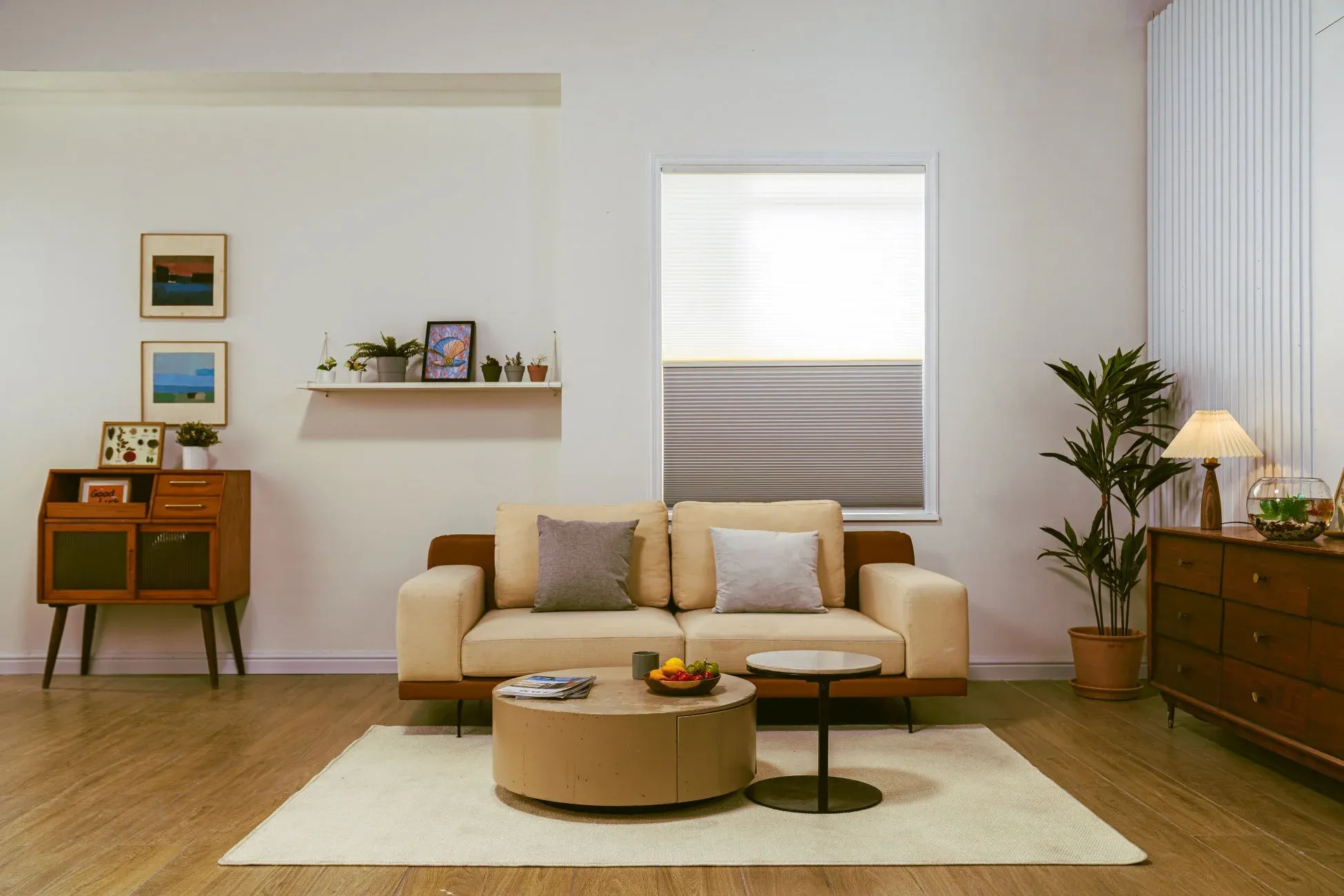 ベージュのソファと丸いコーヒーテーブルが置かれた、明るく居心地の良いリビングルーム