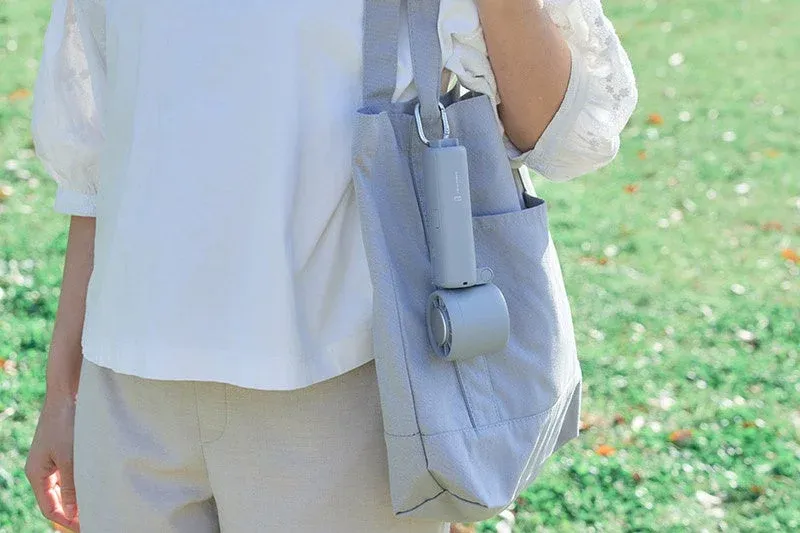 女性がグレーのトートバッグに携帯用扇風機を吊り下げている
