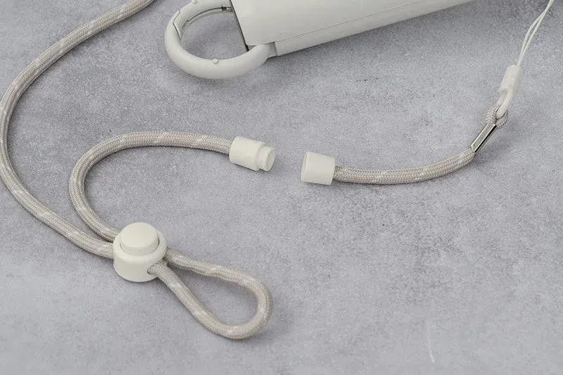 グレーの編み込みストラップとその白いプラスチック製接続部品および長さ調整部品をクローズアップで捉えた画像