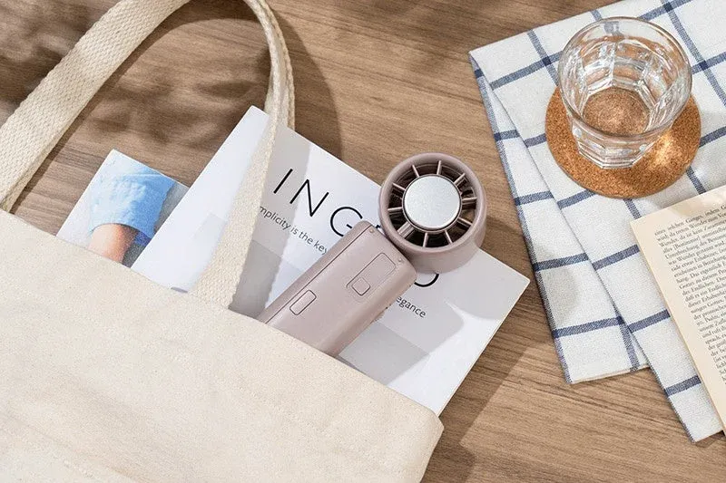 キャンバス地のトートバッグから顔を出す雑誌とポータブル扇風機