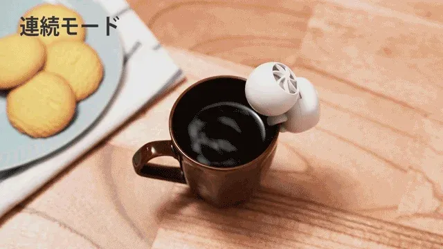 温かいコーヒーが入ったマグカップに、小型の白いデバイスが取り付けられている
