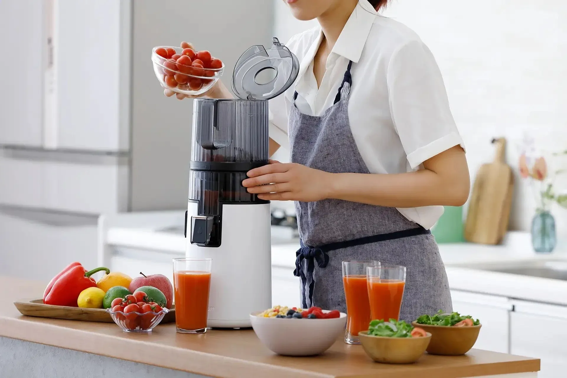 女性がジューサーで野菜を投入する様子