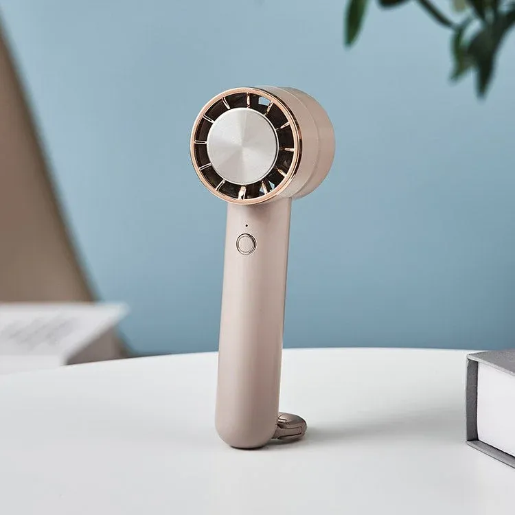ベージュとローズゴールドが特徴のモダンなハンディファンが白いテーブルに置かれています