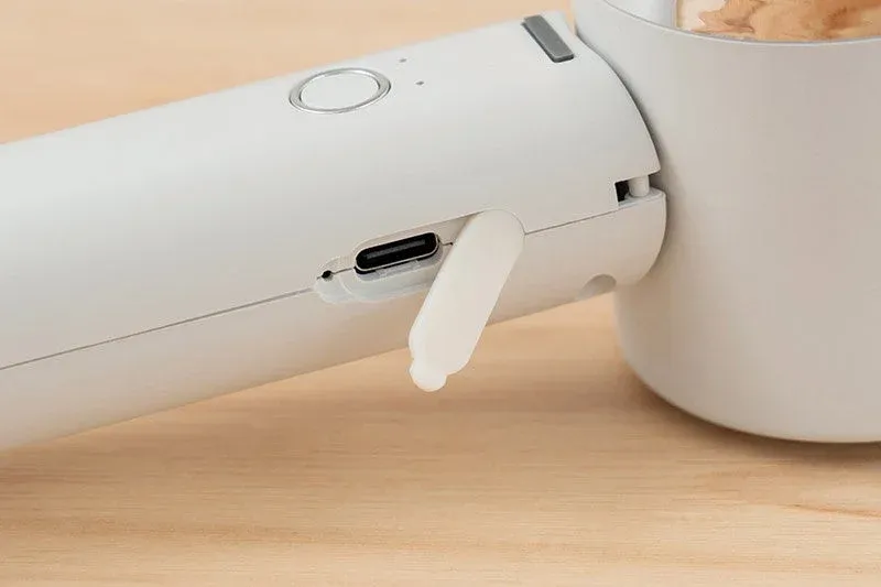 白い電子機器のUSB-C充電ポートがフタを開けた状態で写っており、電源ボタンとインジケーターライトが見えます