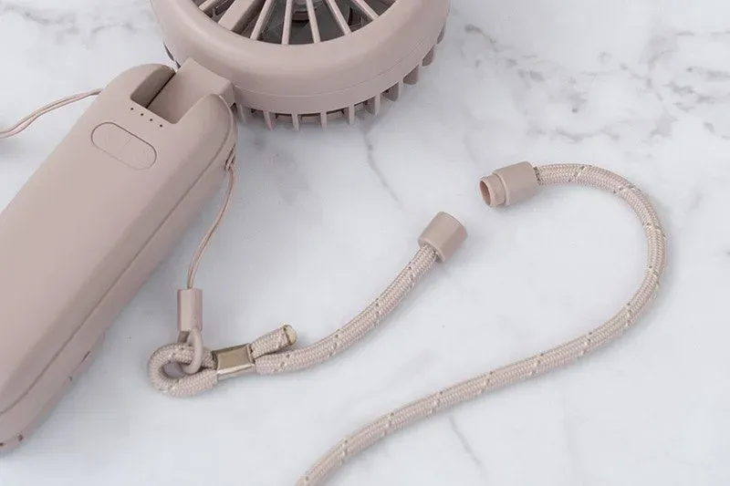 淡いピンク色の携帯扇風機と、それに取り付けるストラップの一部