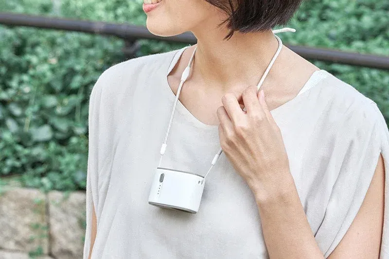 屋外で首掛け扇風機を装着している女性の姿